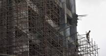 Indian labourers climb up a scaffolding