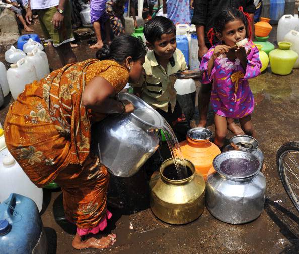 An Indian woman fills a pot with drinkin
