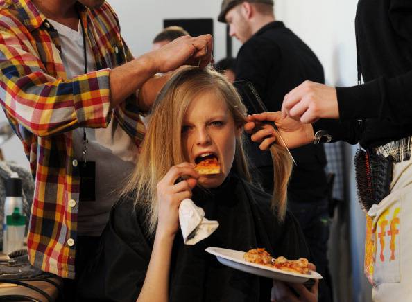 A model takes a bite of pizza while she