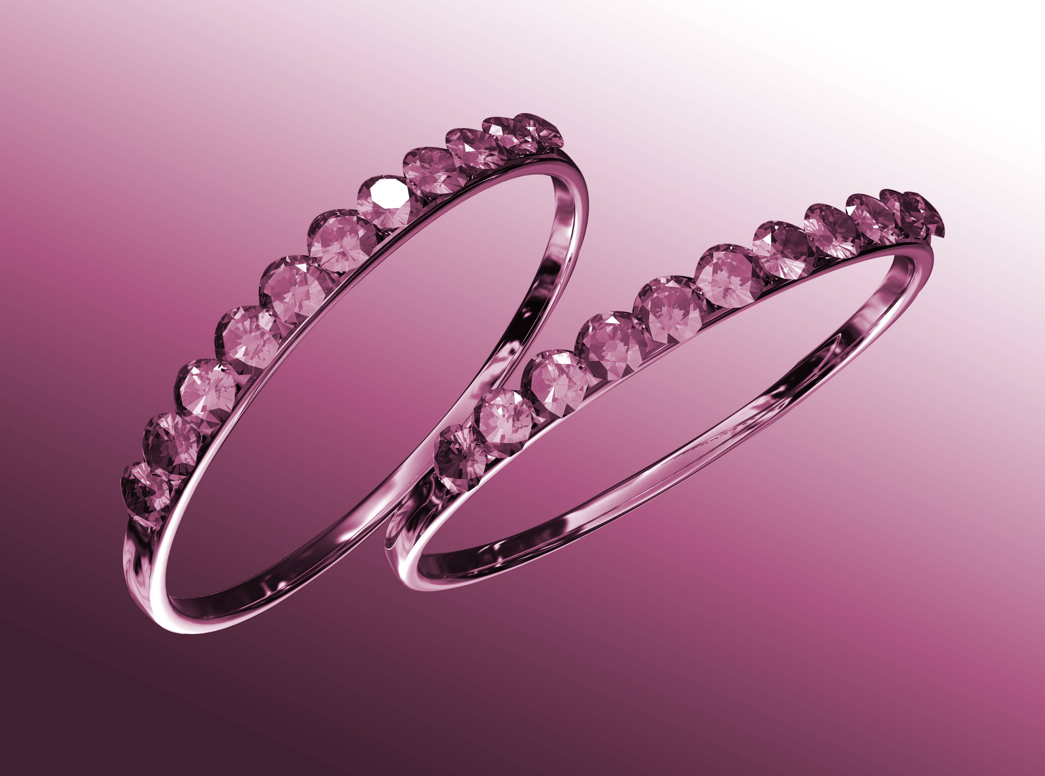 Two rings with diamonds against a pink background