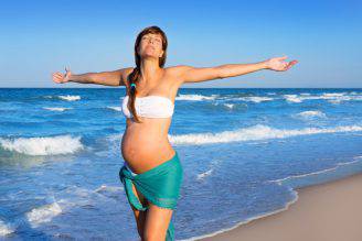 Beautiful pregnant woman walking on blue beach