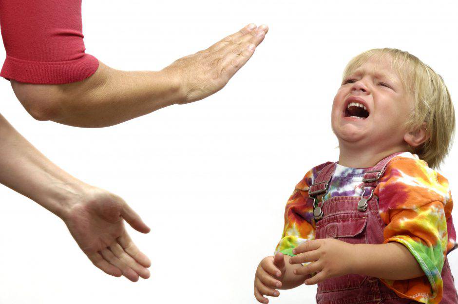 A photograph of a small child having a tantrum with an adult trying to calm him.