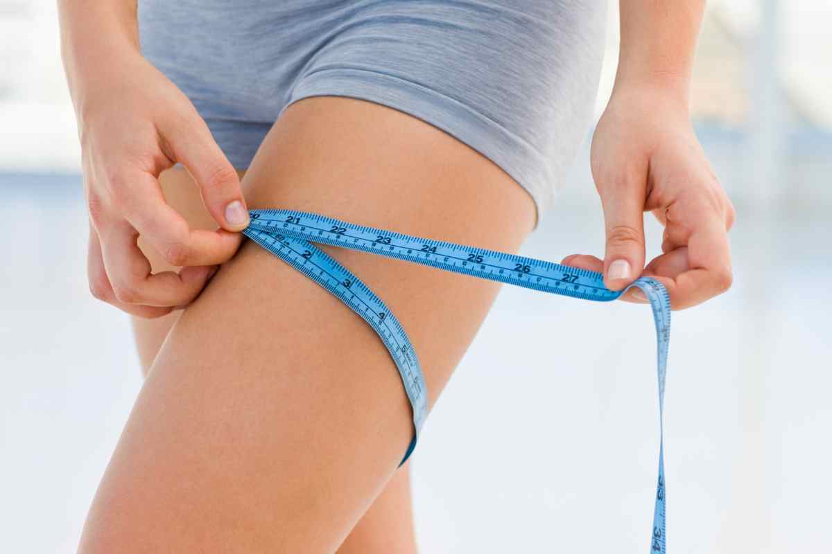 ragazza che si misura la circonferenza della coscia con un metro