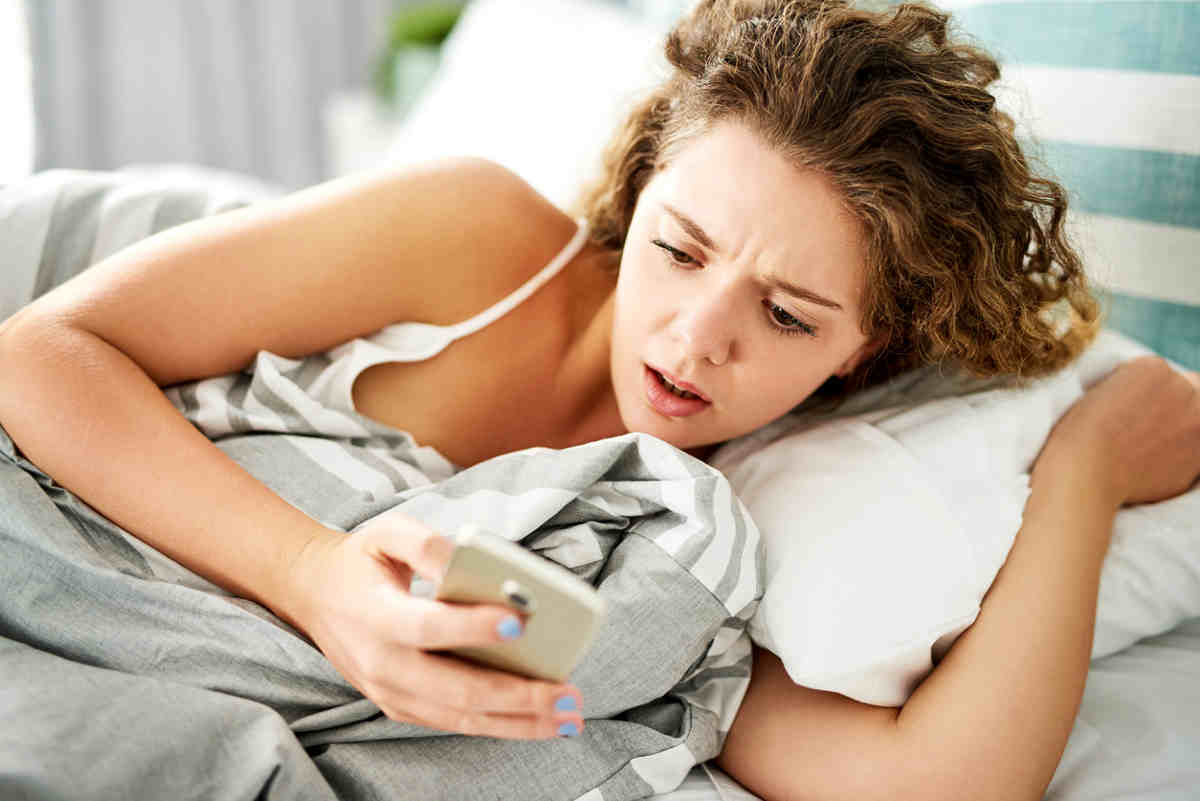 donna a letto con smartphone