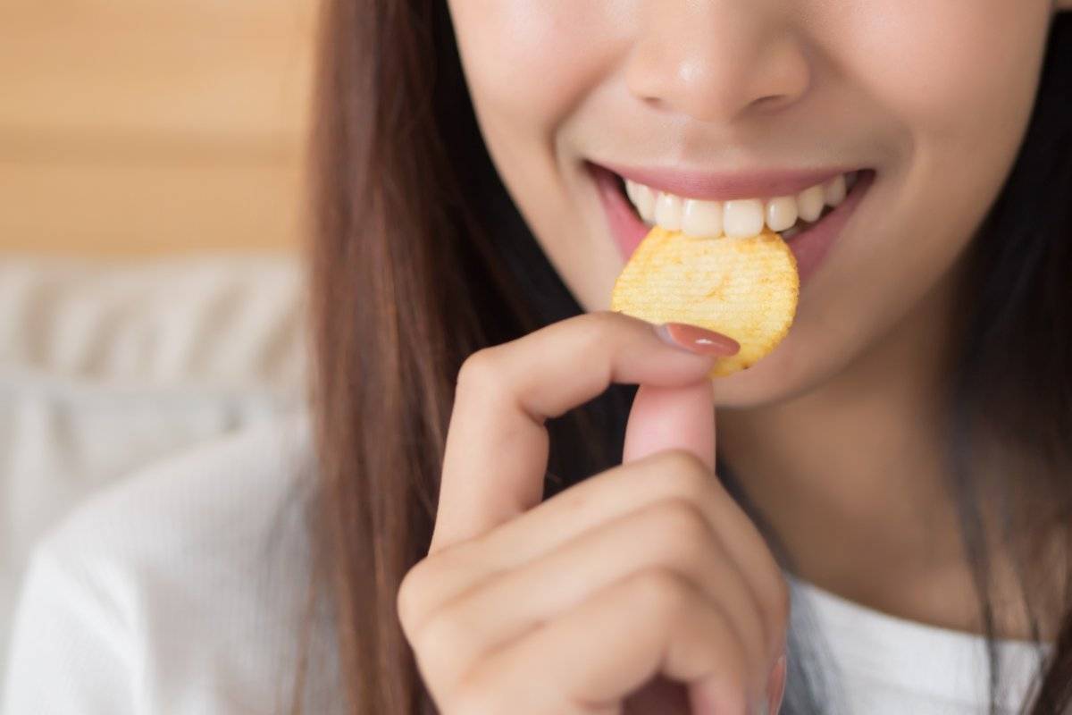 Giovane donna che mangia patatina fritta