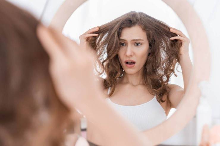 donna si guarda i capelli allo specchio 
