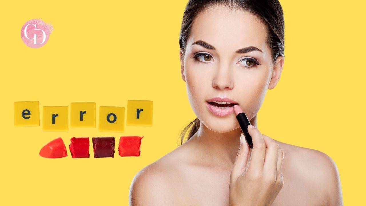 donna si applica il rossetto su sfondo giallo