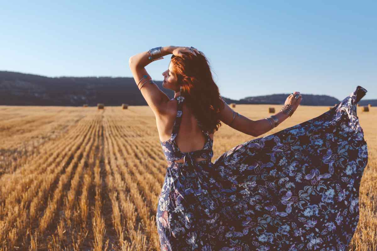 ragazza in abito floreale di spalle in un campo di grano