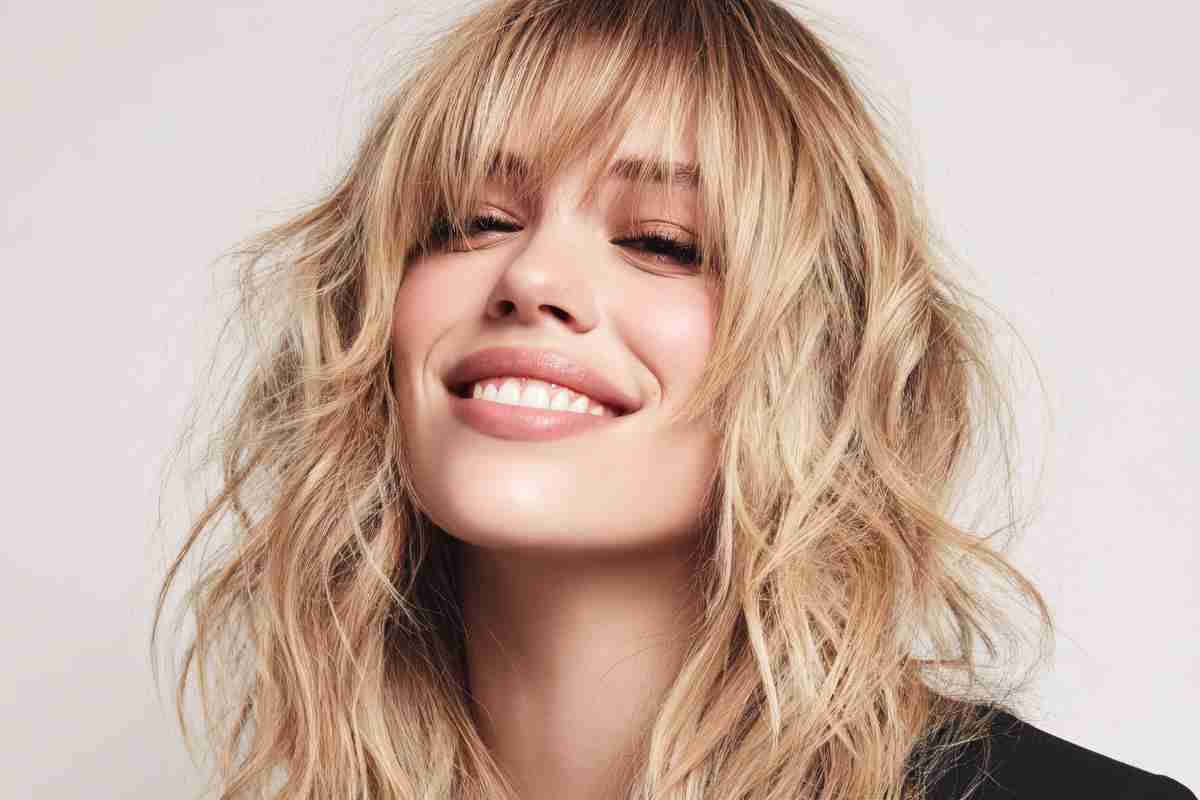 ragazza sorridente con naso lungo ha un taglio capelli scalato con frangia