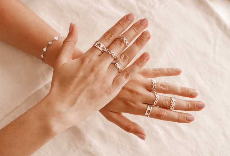 mani di donna con tanti anelli dorati