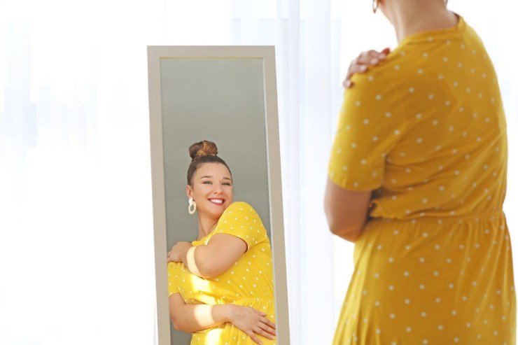 Donna con il vestito giallo allo specchio felice