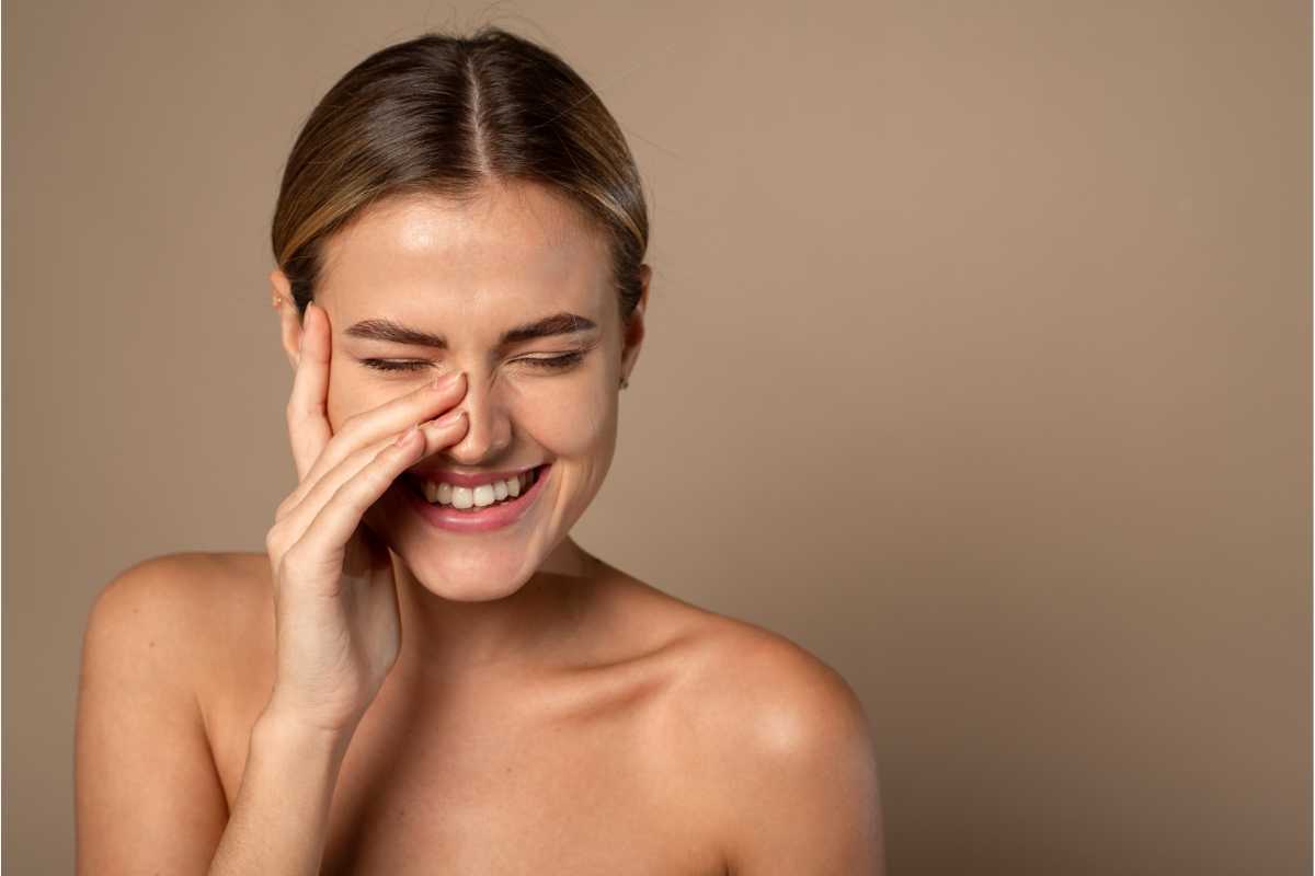 ragazza che sorride e si tocca il viso