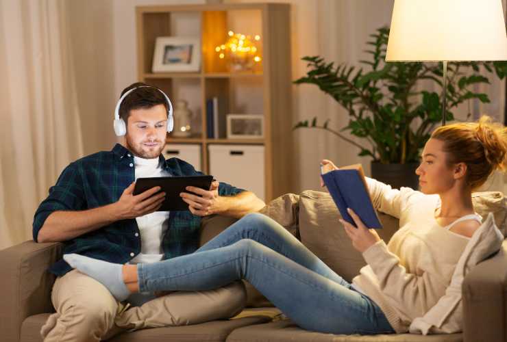 coppia sul divano che legge e sente la musica