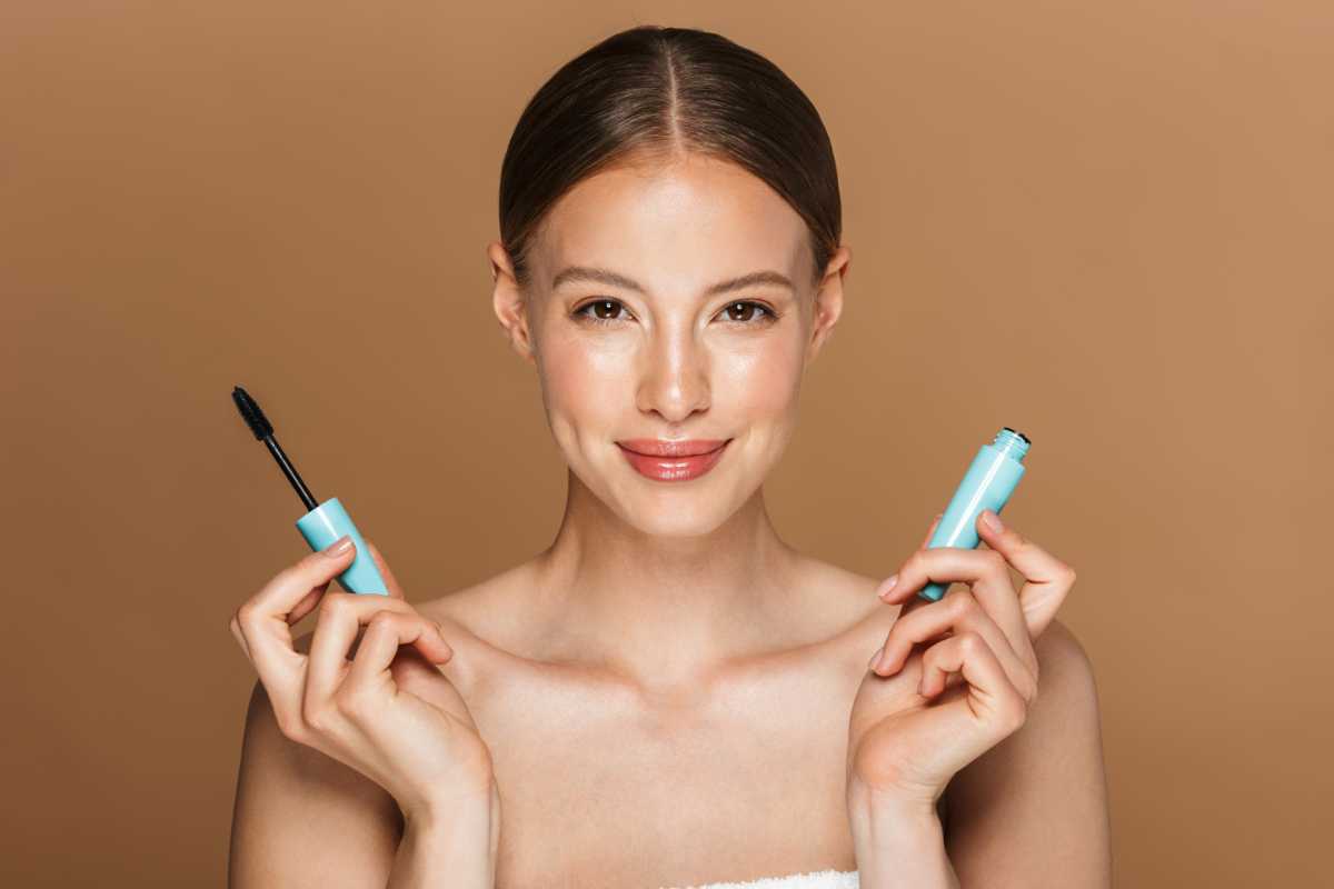 donna sorridente con tubetto di mascara