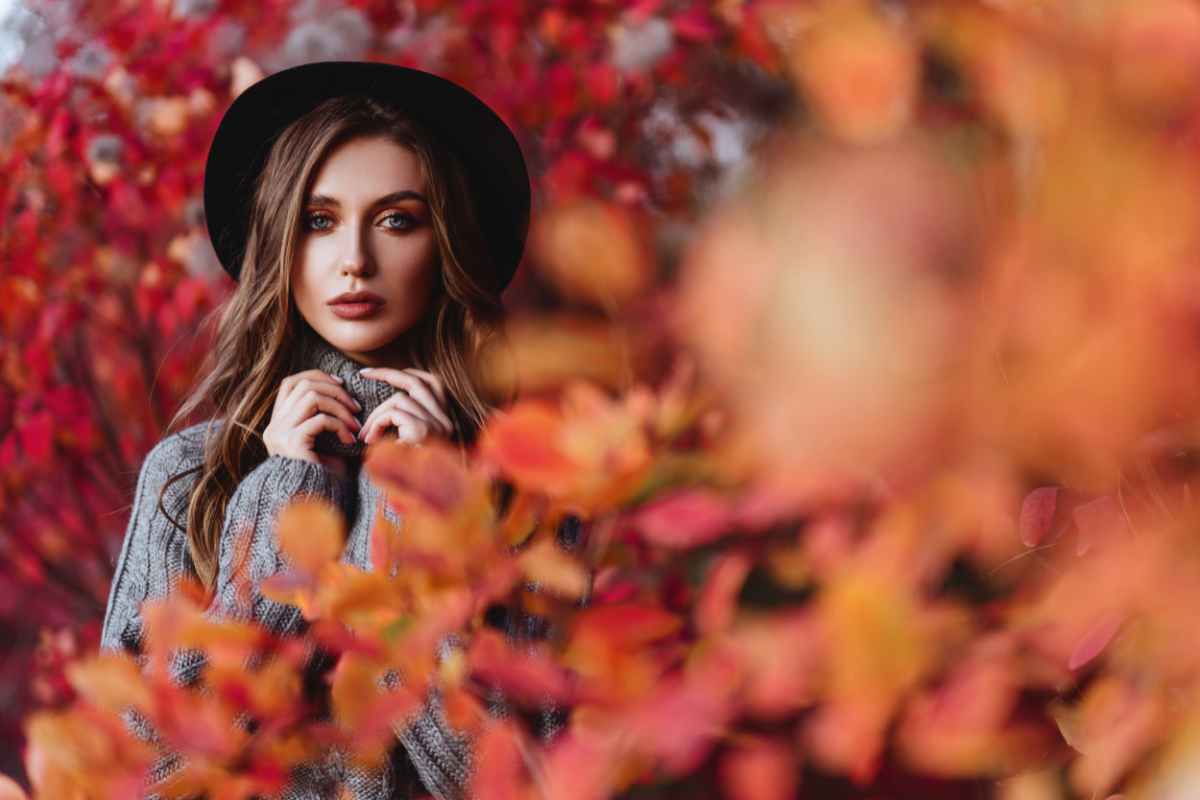 ragazza con cappello dietro a foglie rosse