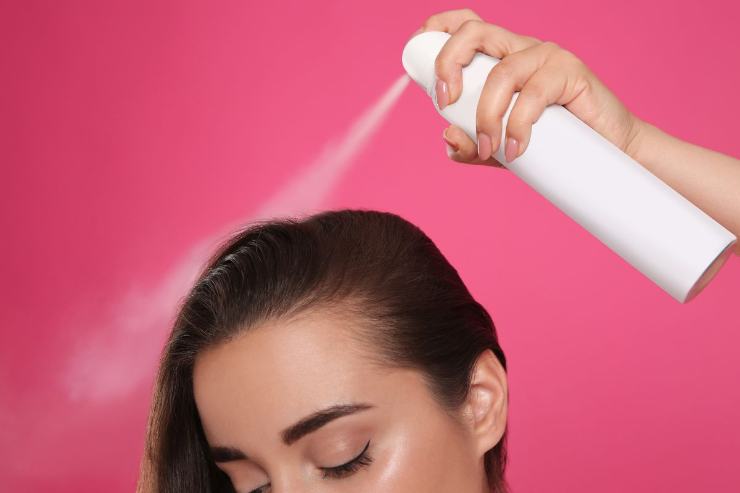 Donna che spruzza lacca 