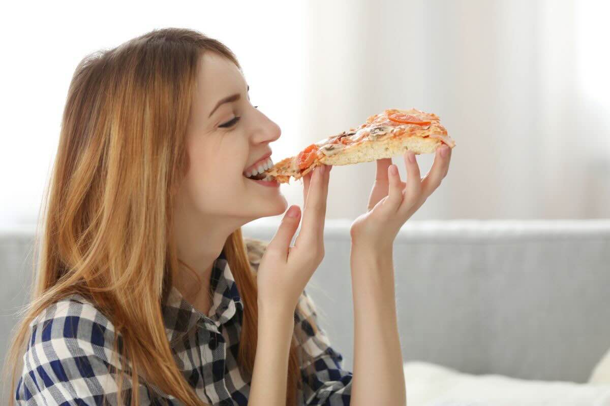 Ragazza mangia trancio di pizza