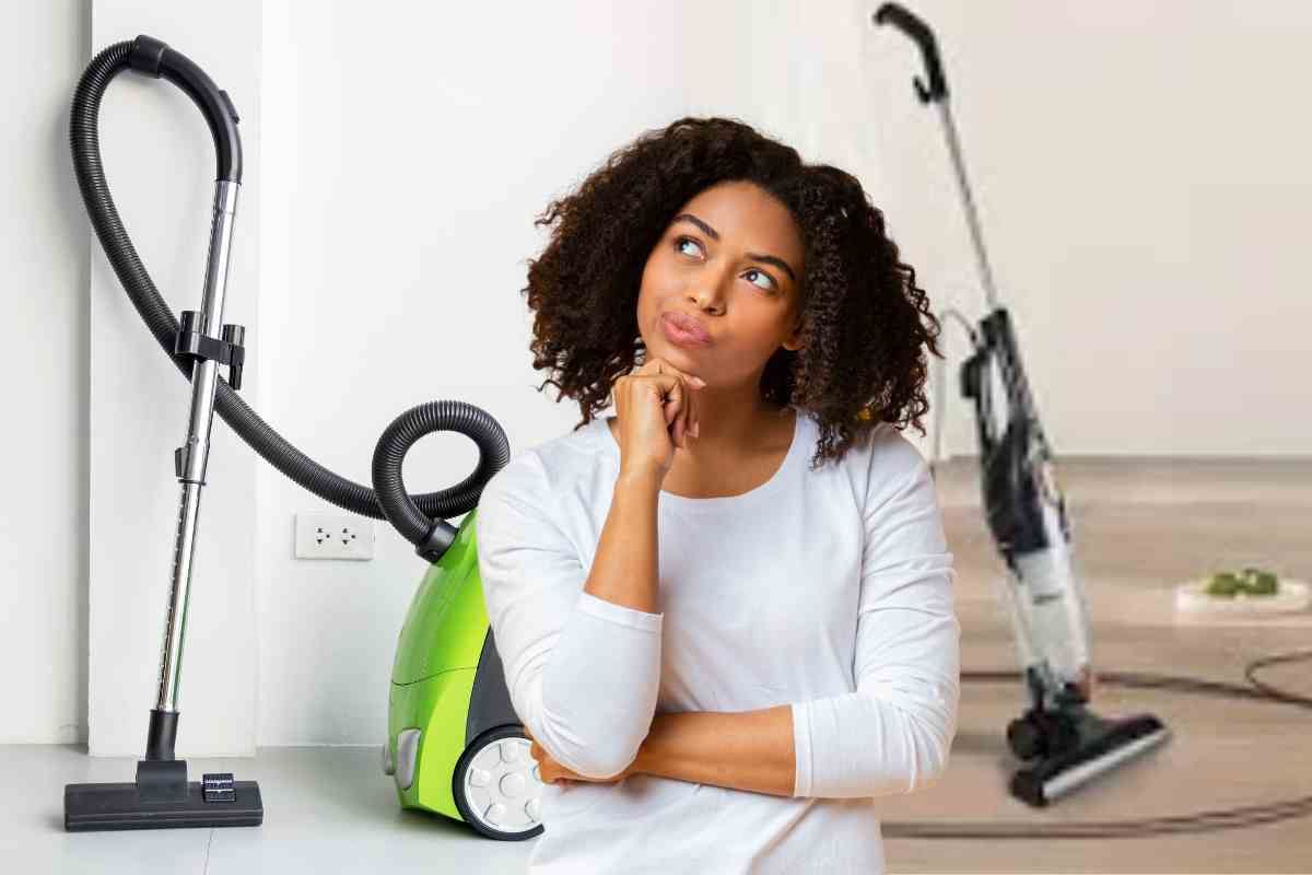 donna indecisa tra scopa elettrica e aspirapolvere