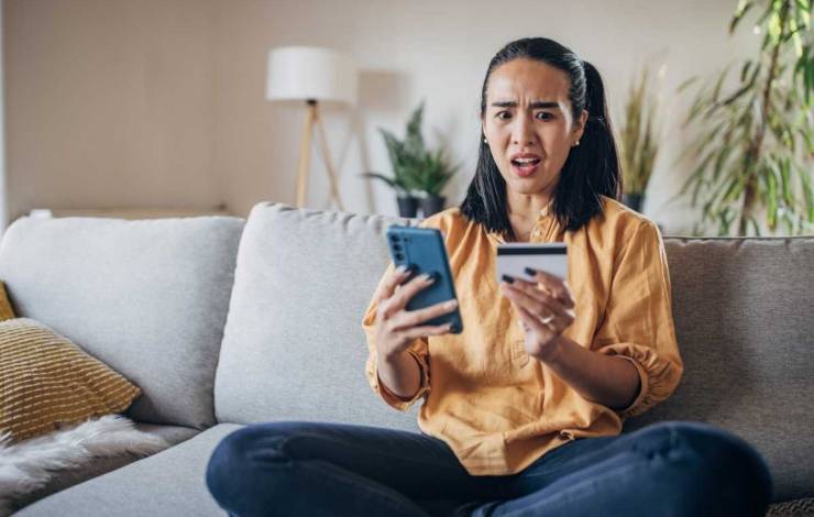 Donna con carta e cellulare sul divano