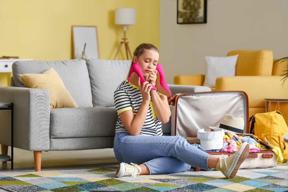 Donna con scarpe fucsia e valigia aperta vicino a lei
