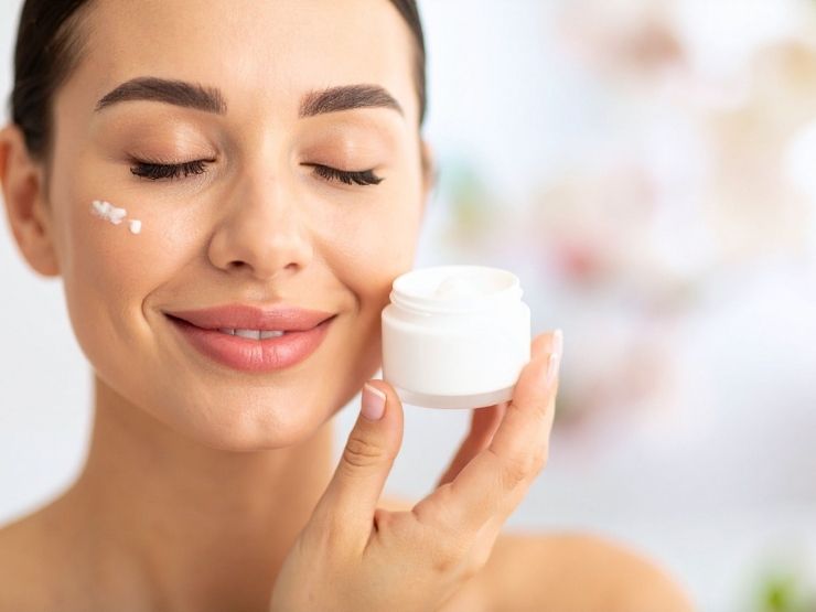 donna che avvicina al viso la crema in barattolo