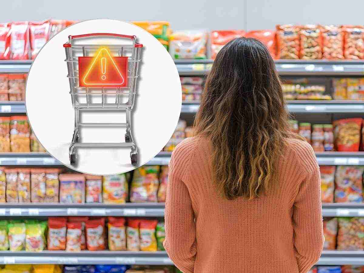donna di spalle al supermercato davanti scaffale merendine, carrello della spesa con simbolo pericolo in evidenza