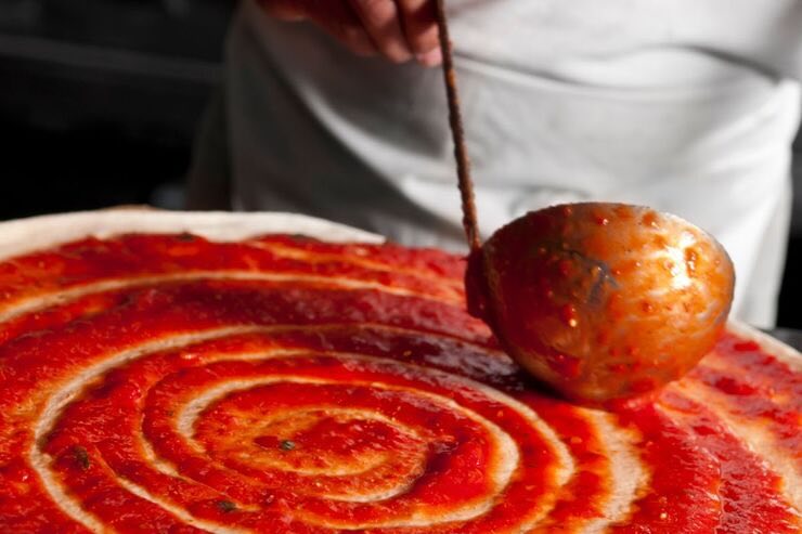 uomo che mette salsa sulla pizza 