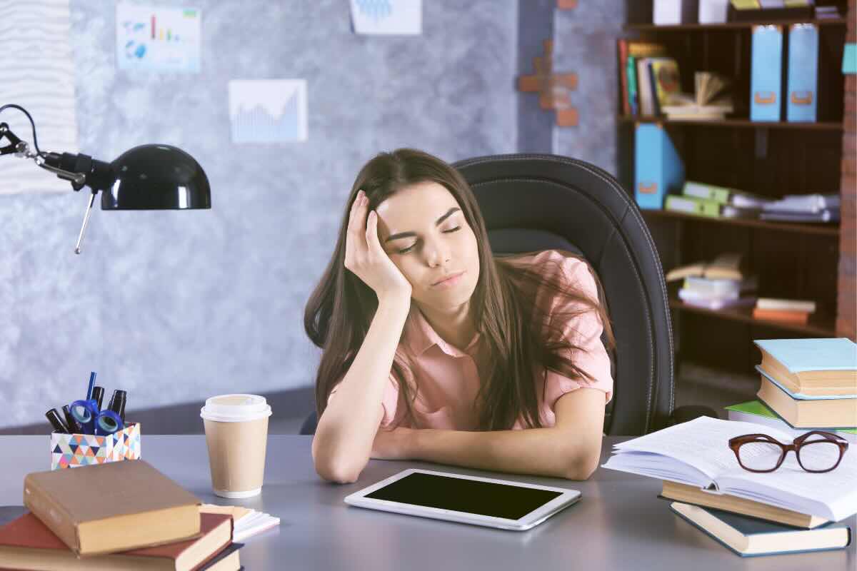 donna alla scrivania con occhi chiusi 
