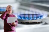 Uomo preoccupato per l'aumento della bolletta con fornello a gas acceso sullo sfondo
