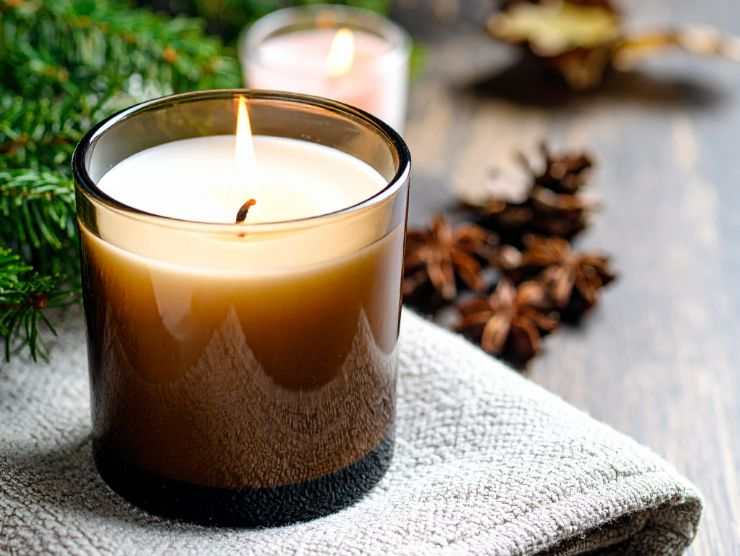 candela in vetro accesa e decorazioni natalizie tutte intorno