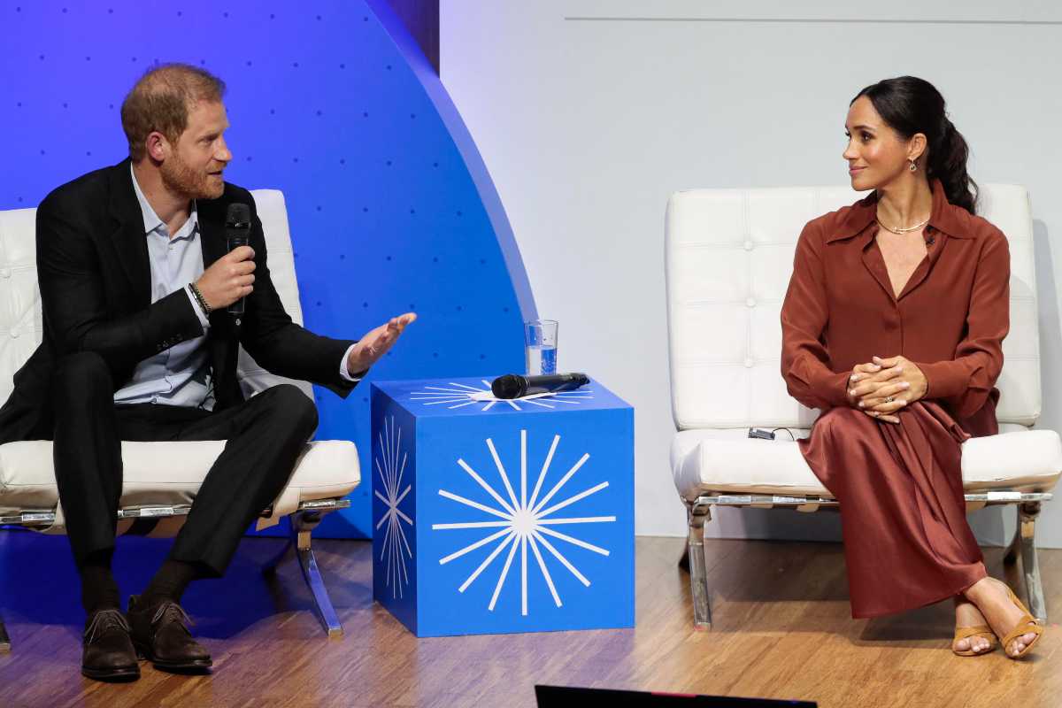 Harry e Meghan seduti che parlano al pubblico ad un evento