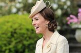 Kate Middleton sorride di profilo. Indossa un tailleur giallo con cappellino e i capelli raccolti.