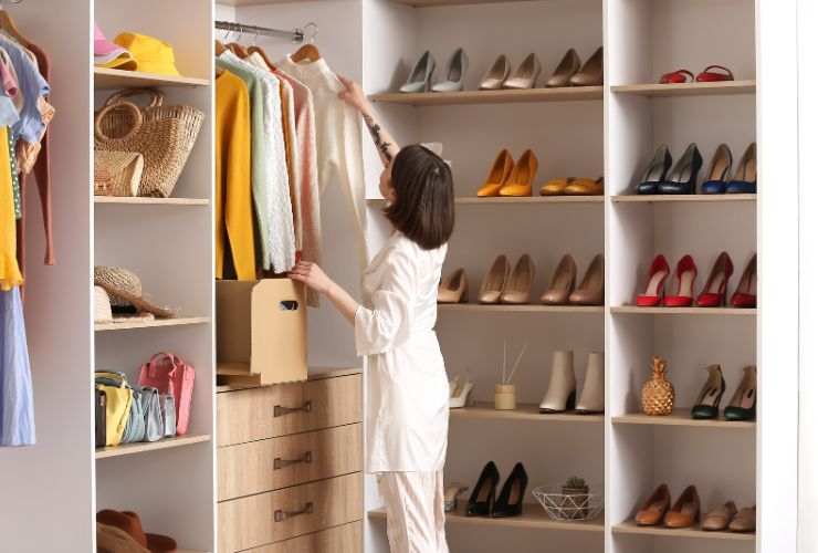 donna che sistema armadio pieno di scarpe e vestiti