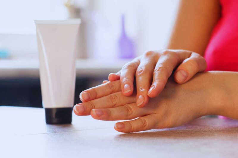 Mani di donna con accanto il tubetto di una crema