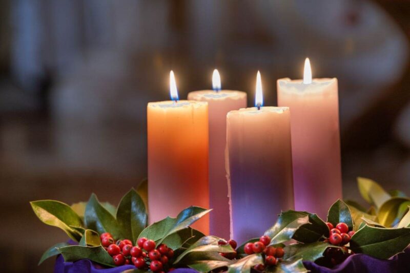 4 candele accese al centro di una composizione natalizia