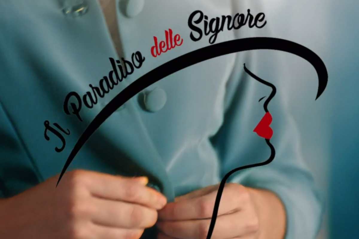 la critta de il paradiso delle signore sul camice di una donna verde e le mani in primo piano