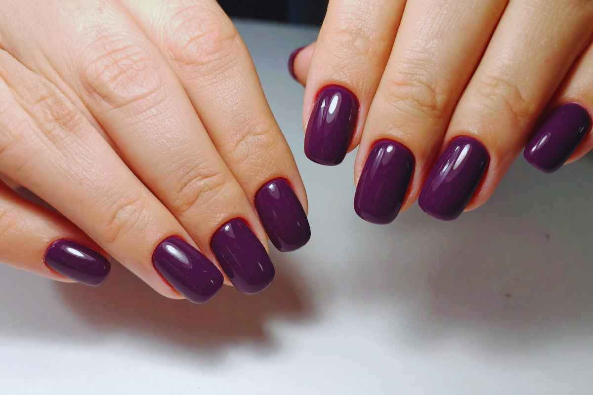 Delle mani con indosso lo smalto viola