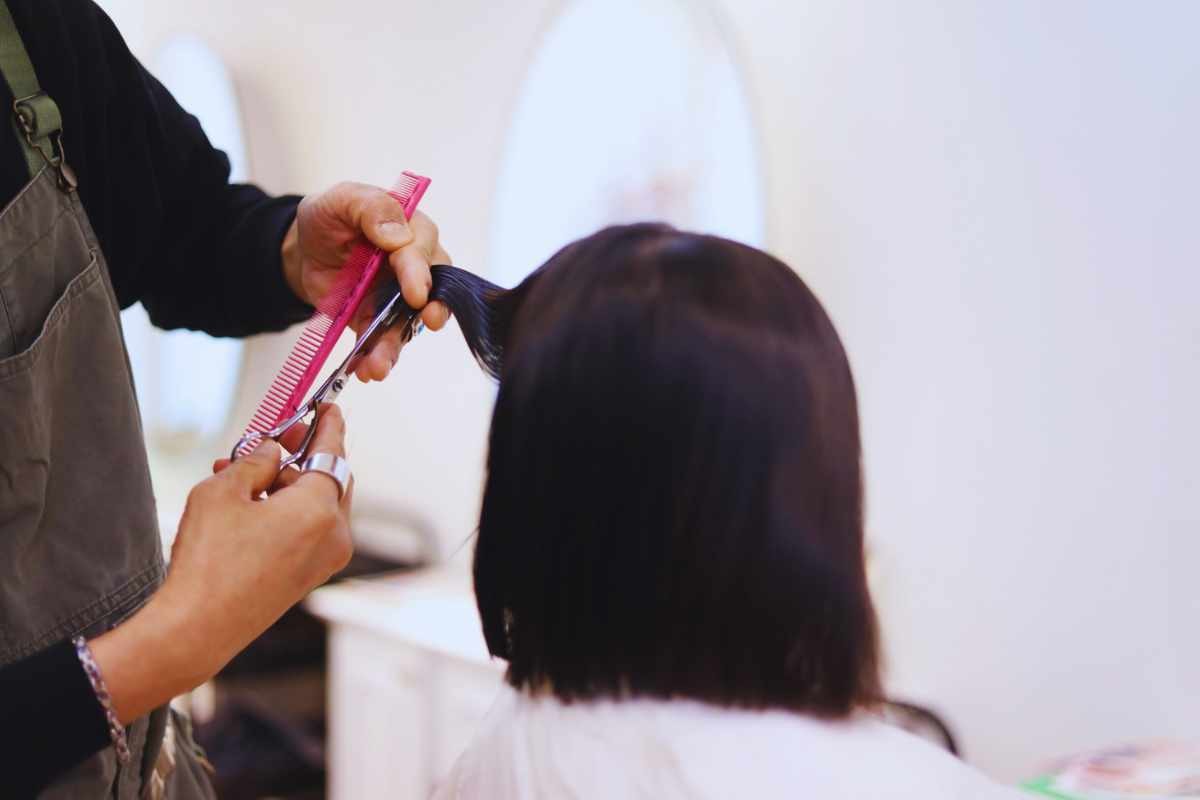 Una donna con dei capelli neri dal parrucchiere durante il taglio