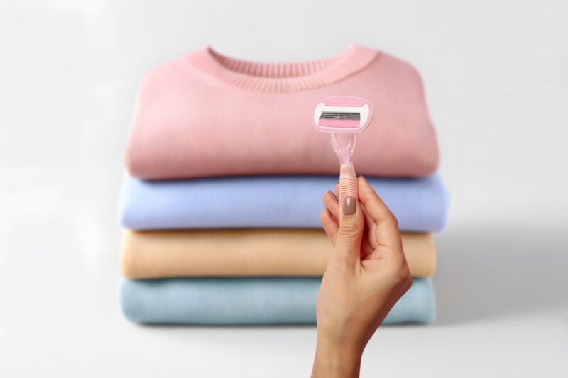 maglioni piegati e donna che mantiene una lametta