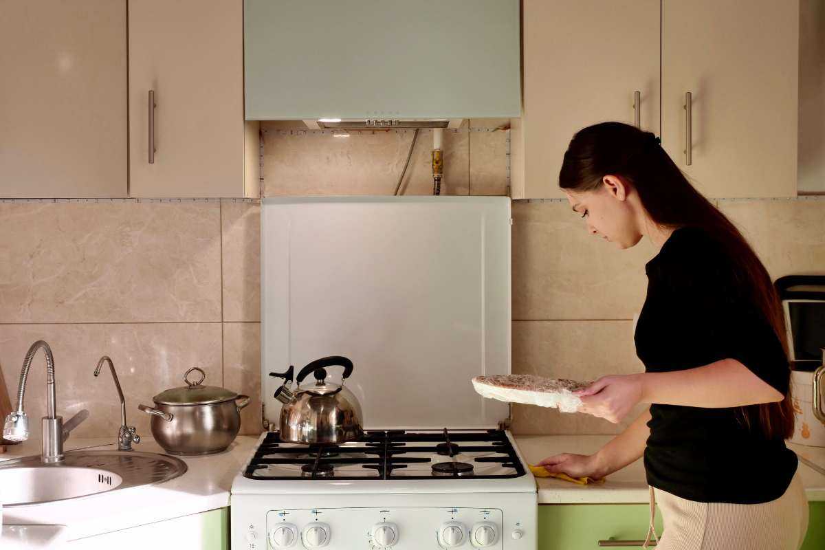 Ragazza che indaffarata nei pressi del bancone della cucina con il bollitore sui fornelli