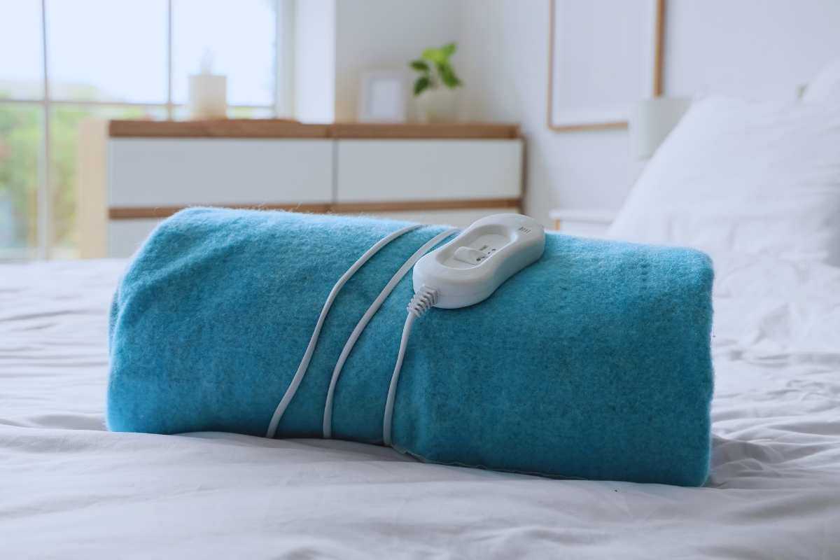 Una coperta elettrica arrotolata e posta su un letto