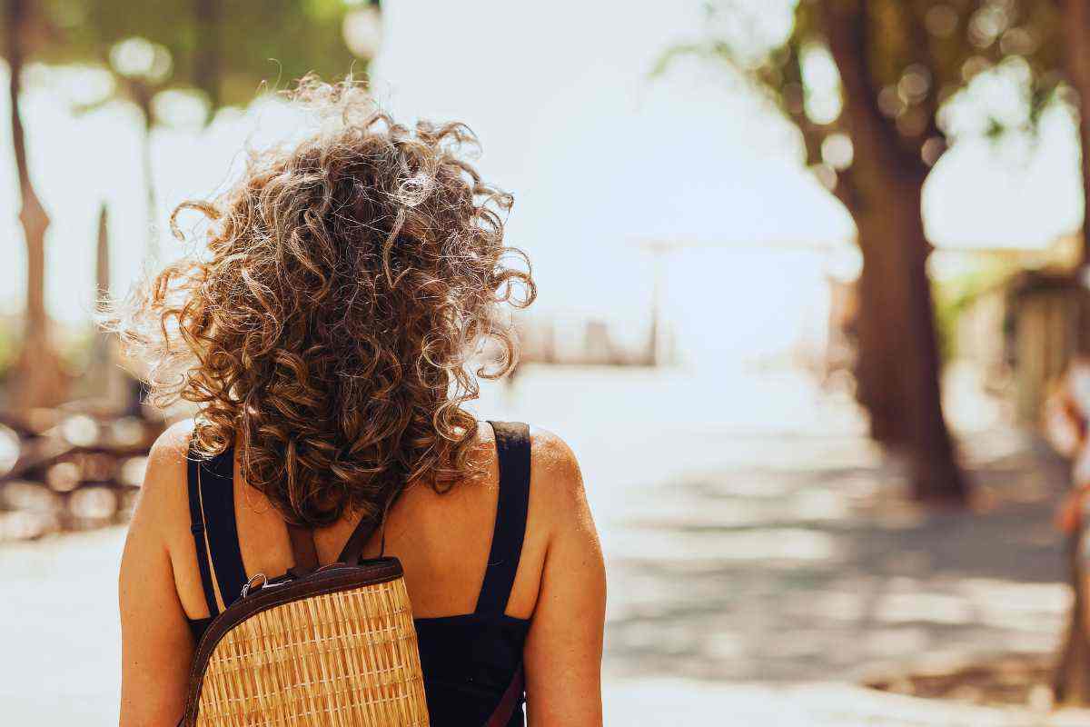 Una ragazza di spalle che cammina con lo zaino in spalla