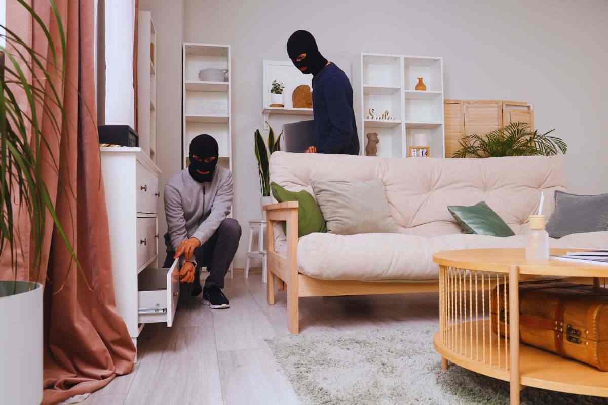 Ladri che frugano dentro una casa, uno guarda nel cassetto di una cassettiera, l'altro è in piedi dietro di lui
