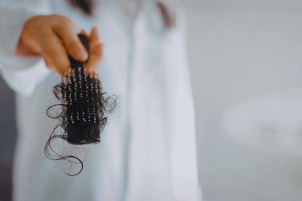 Donna mostra una spazzola piena di capelli