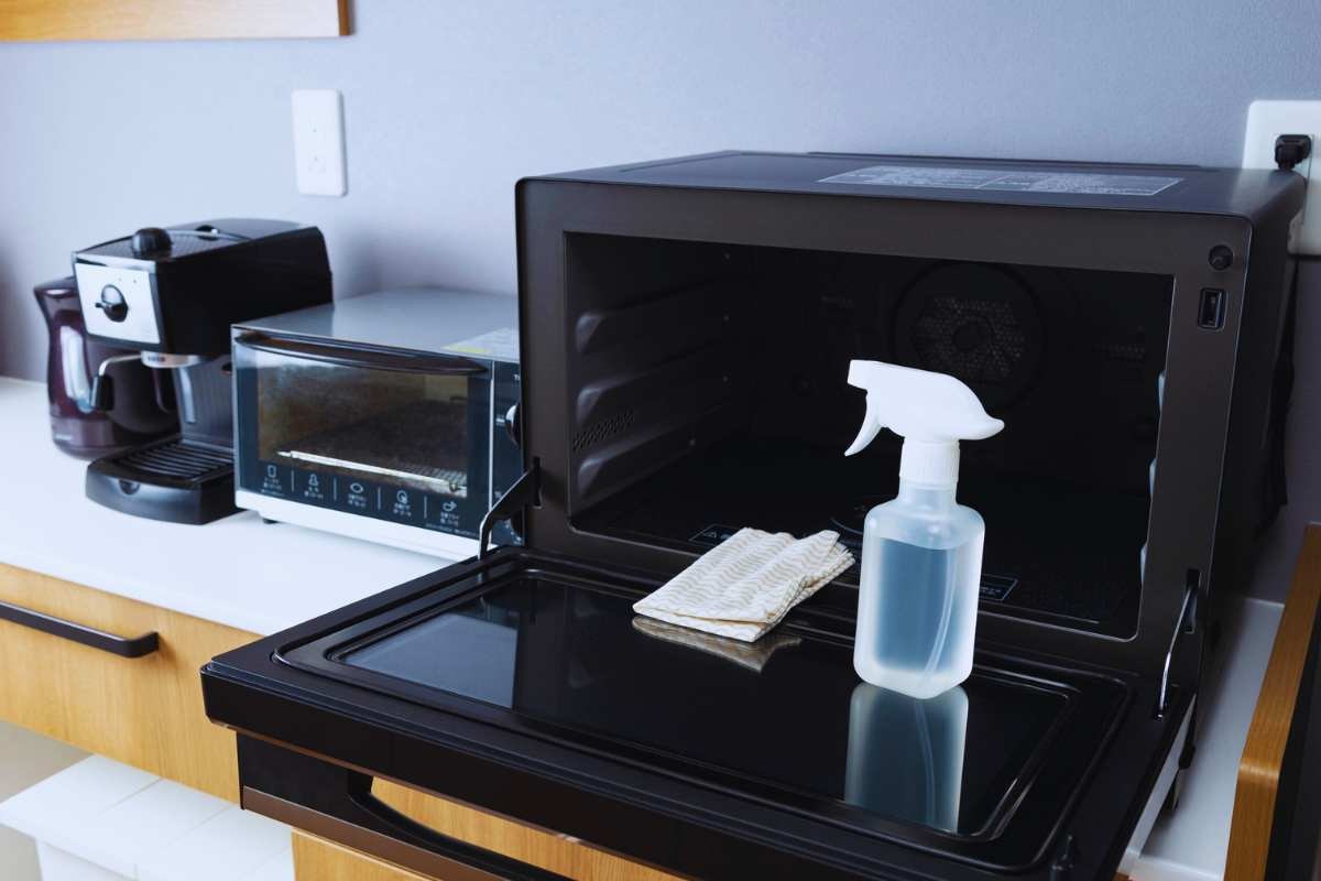 Un forno a microonde con uno spray appoggiato sullo sportello