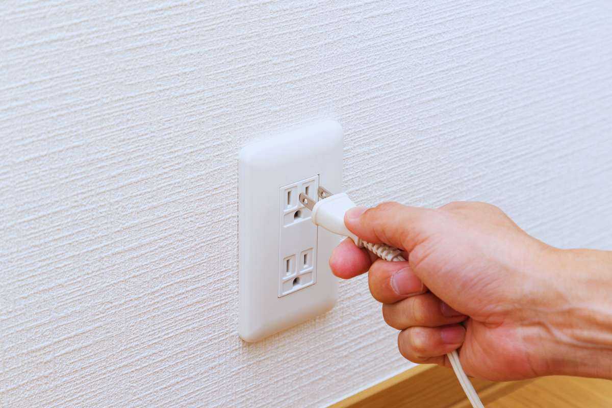 Mano che stacca o attacca una presa dalla corrente